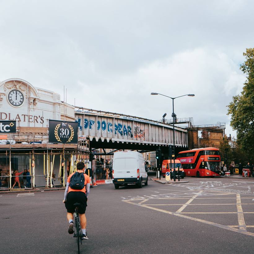 Cyclist riding towards a graffitied railway bridge
