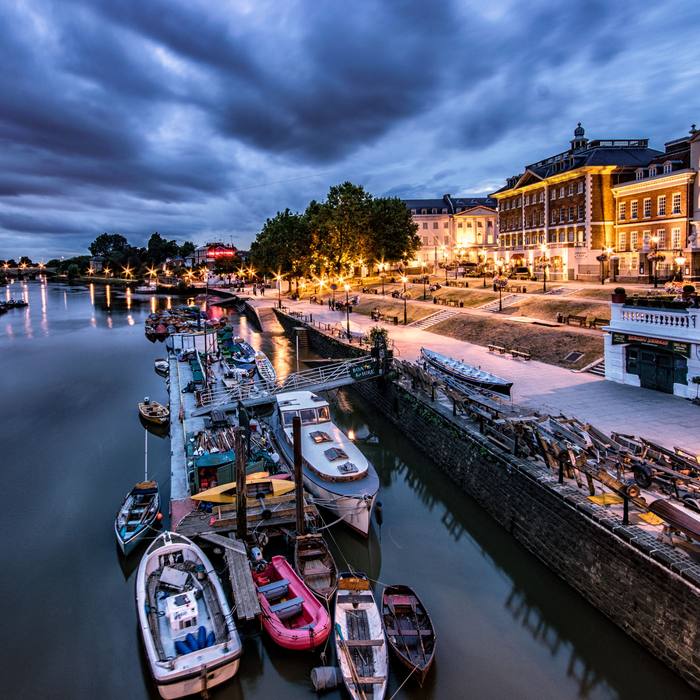 Moored boats along a lit riverside promenade at dusk