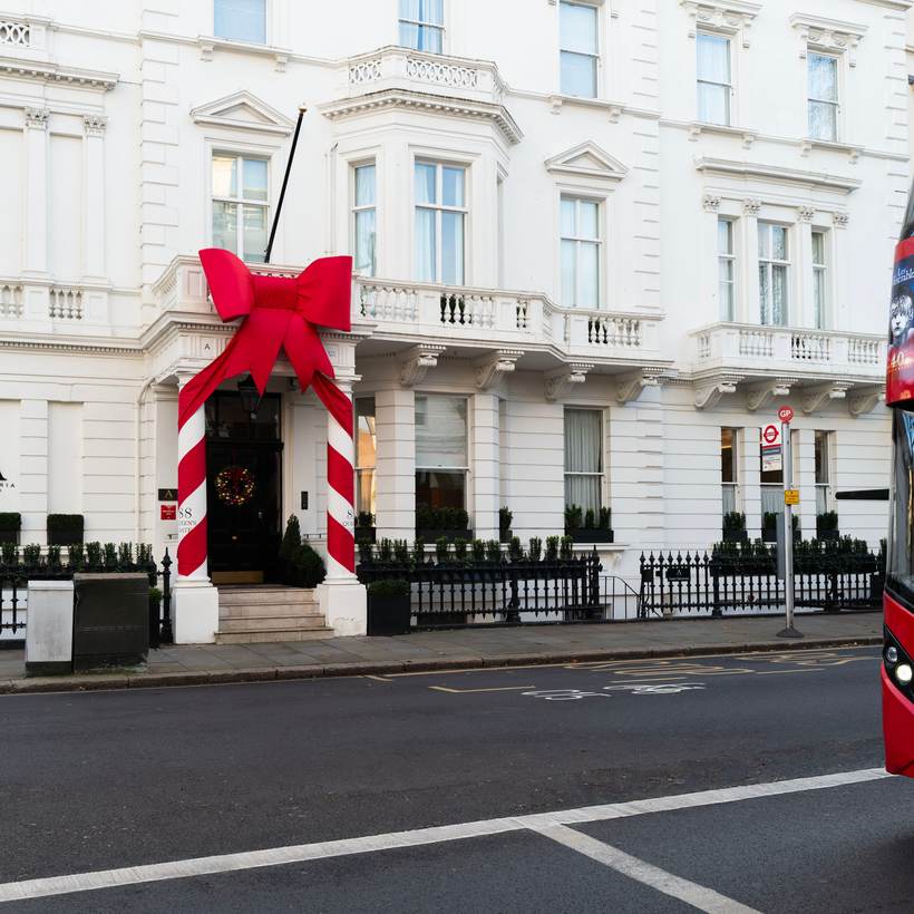 Red double-decker bus passing a white stucco terrace