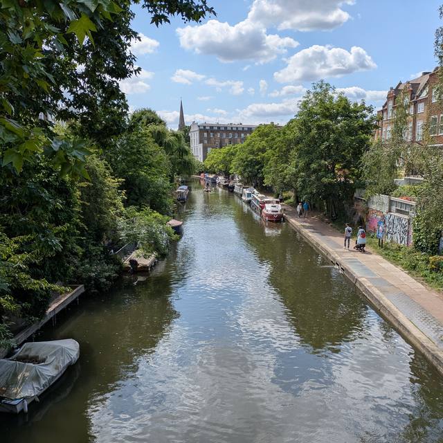 Narrowboats moored along a tree-lined canal towpath