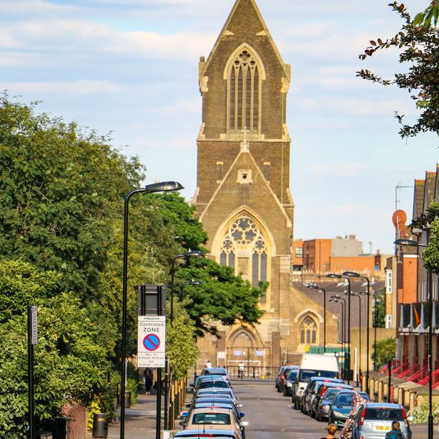 Parked cars on a hill below a tall church tower