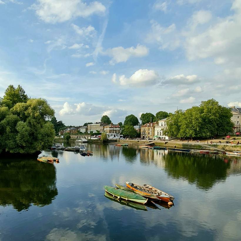 Calm river reflecting clouds beside a wooded bank