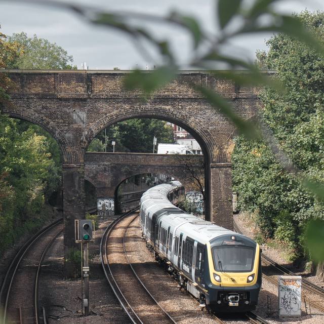 Commuter train emerging from an arched brick viaduct