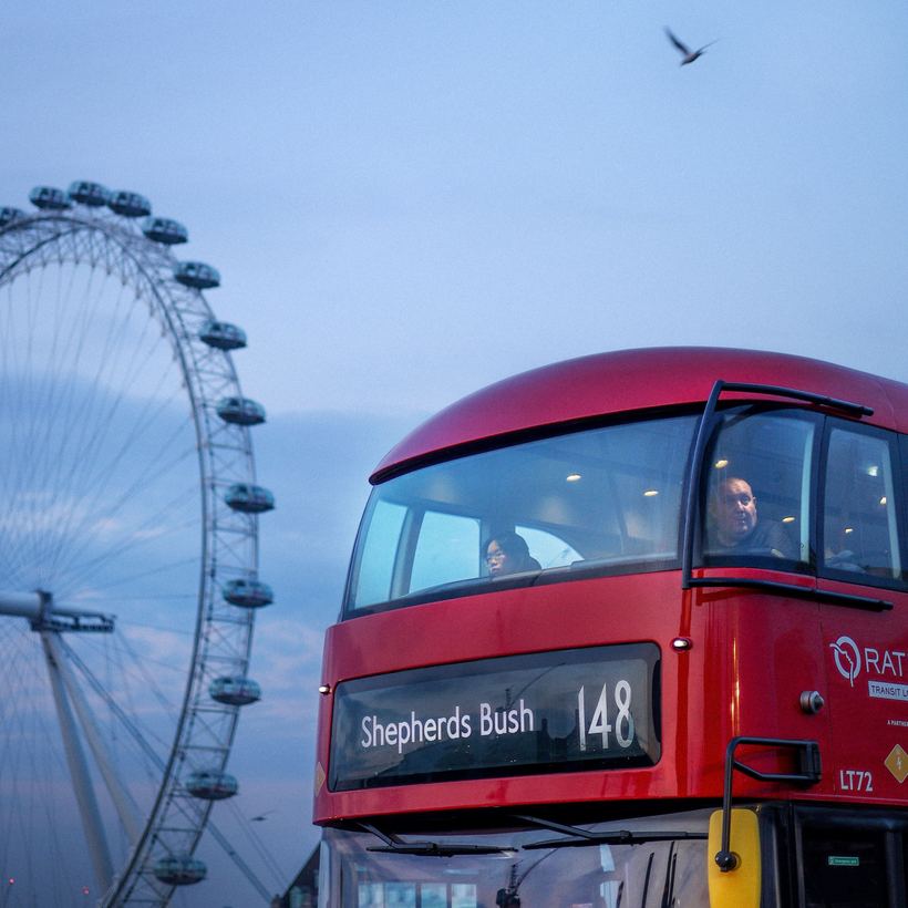 Red double-decker bus in front of a giant observation wheel