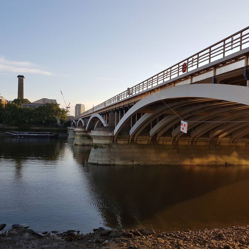 Arched railway bridge spanning the river with a chimney beyond