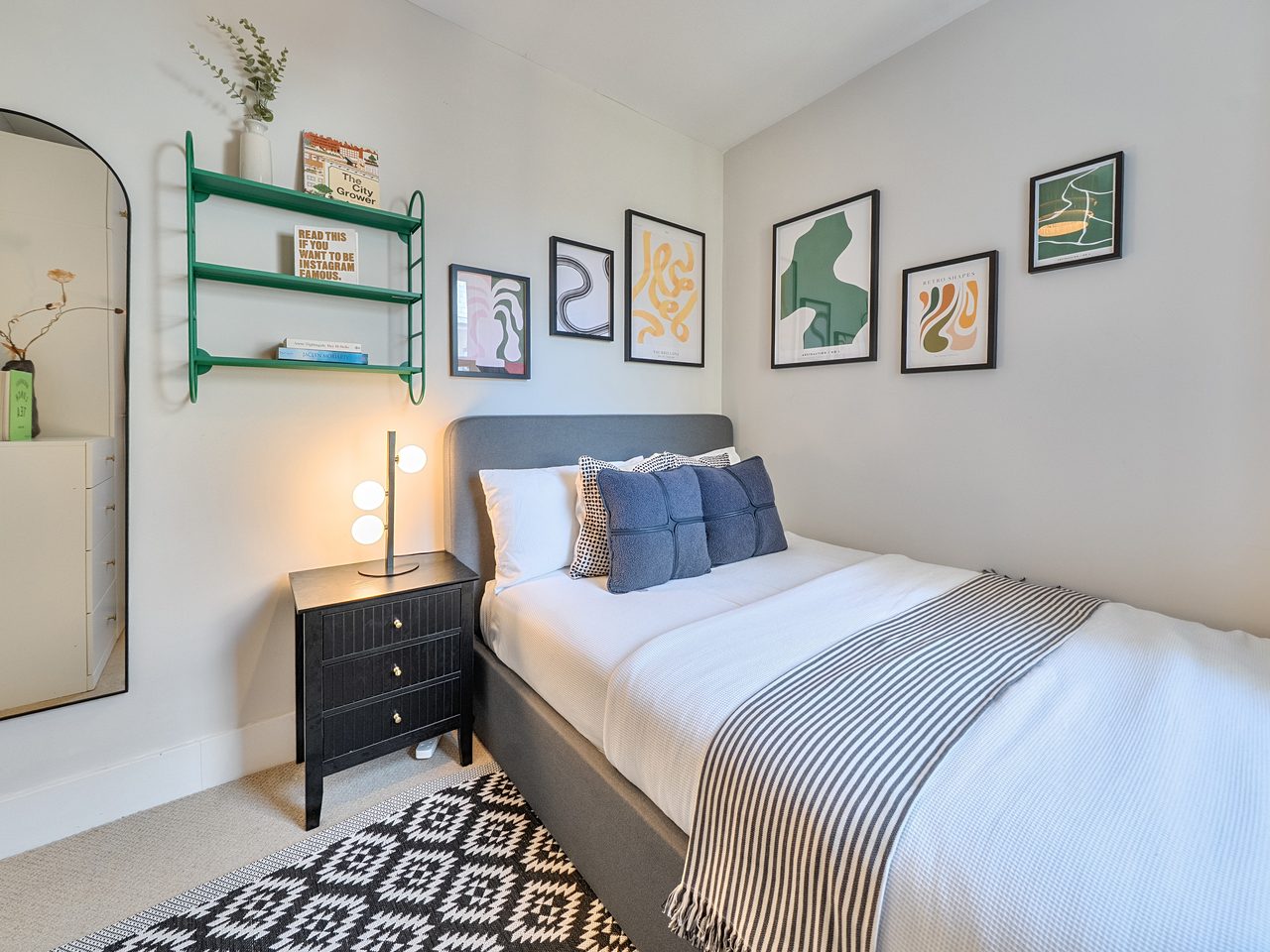 Second bedroom with a gallery wall of prints and a green wall shelf