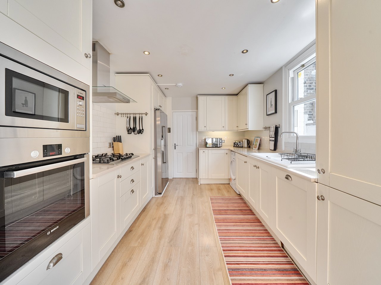 Galley kitchen with cream shaker units and integrated appliances